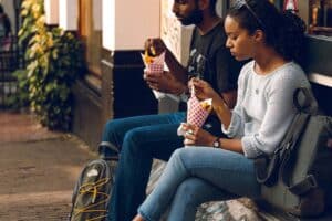 Twee mensen eten op straat friet, of is het toch patat?